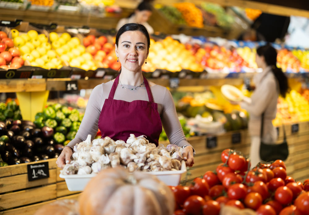saleswoman holds a container of garlic in her hands