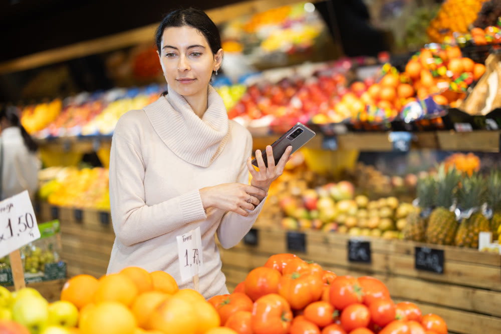 woman with a phone in her hands stands in a grocery store