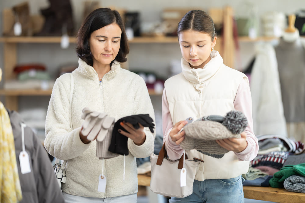 Adult woman and her daughter choose hat and gloves