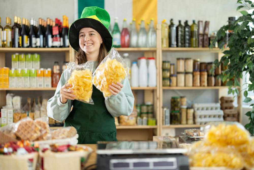 Teenage girl seller offers chips in grocery store