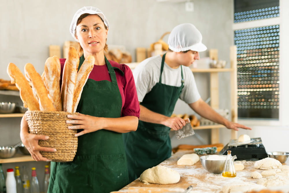 Adult woman baker with basket of baguettes