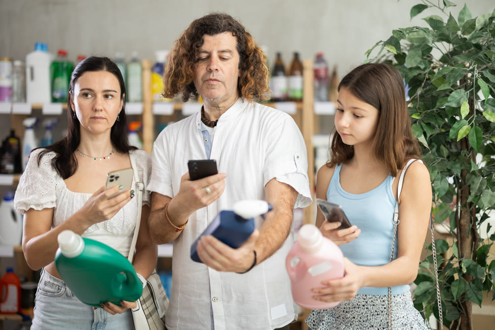 Family scanning cleaning supplies bottles with smartphones in supermarket