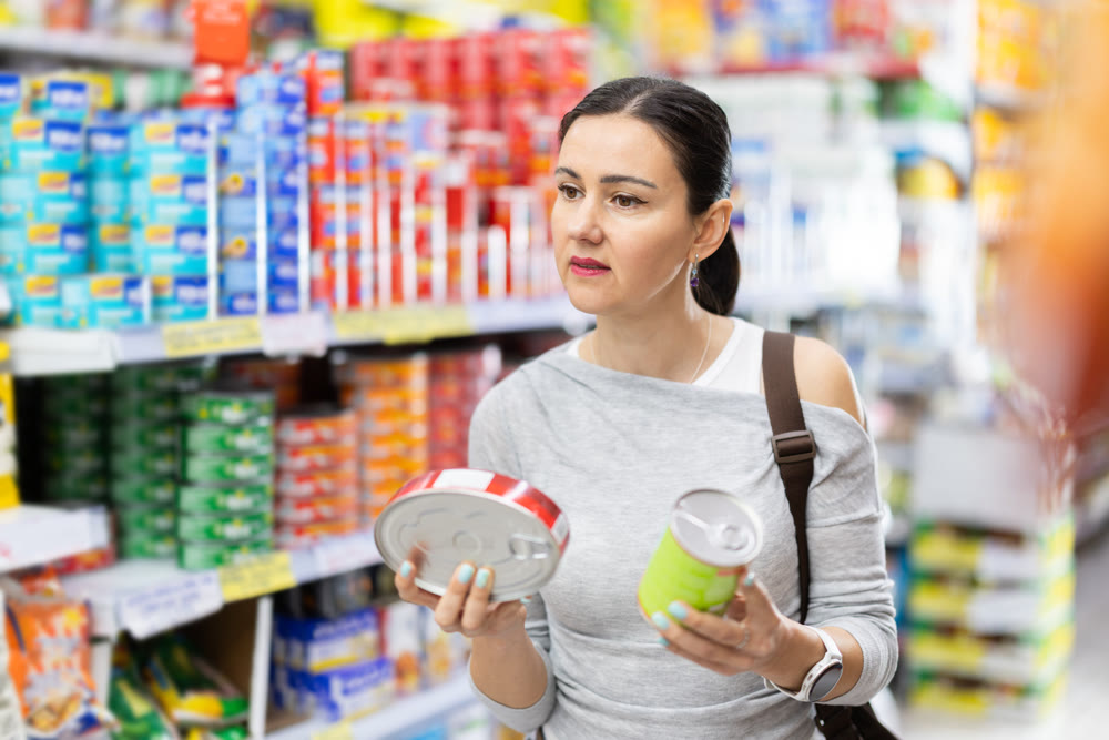 Adult woman chooses canned goods in store