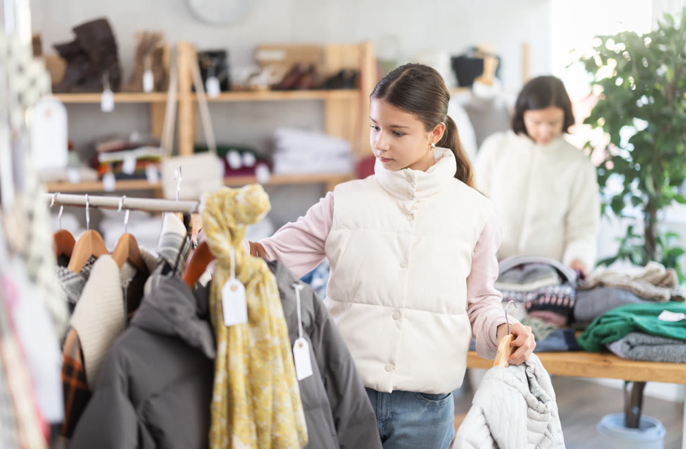 Teenage girl chooses down jacket in store