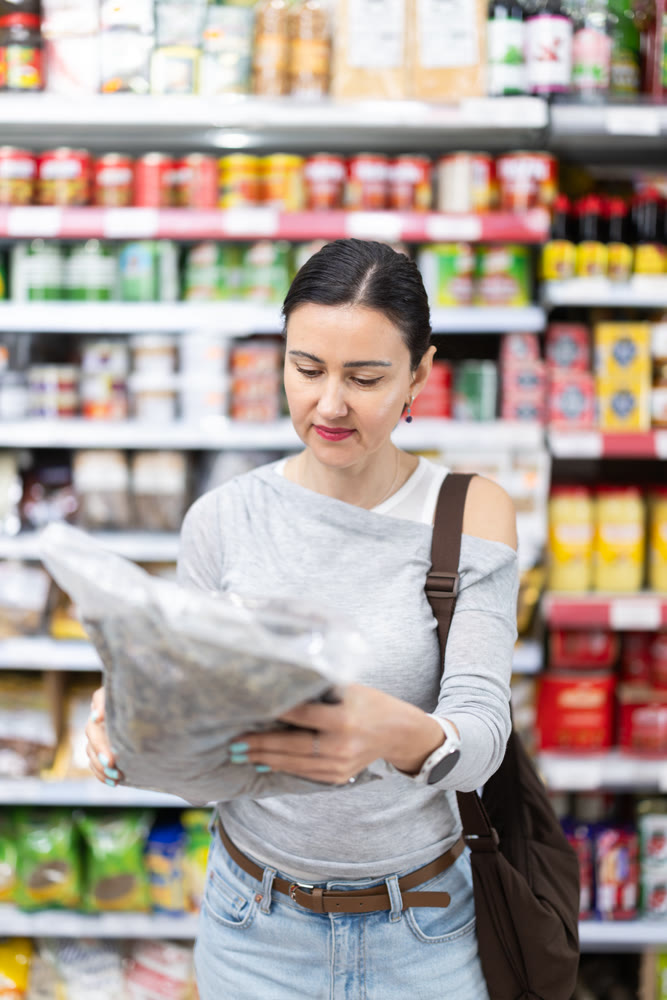 Woman customer in supermarket choose dried fish, buy food stuff in grocery store