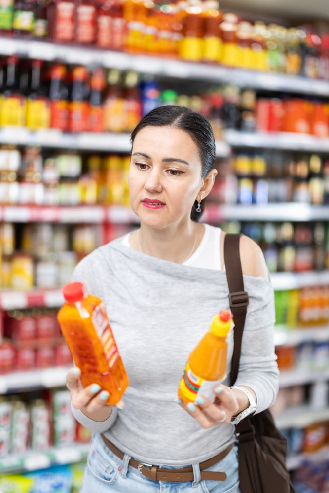 Woman customer in supermarket choose sauce, buy food stuff in grocery store