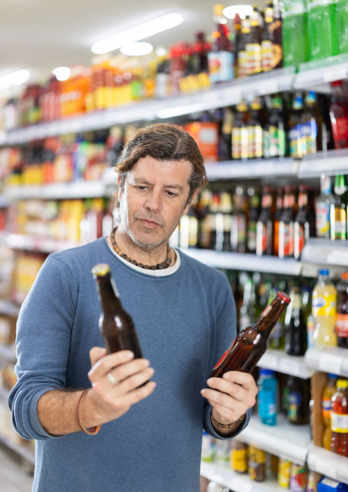 Man customer in supermarket choose beer, buy food stuff in grocery store