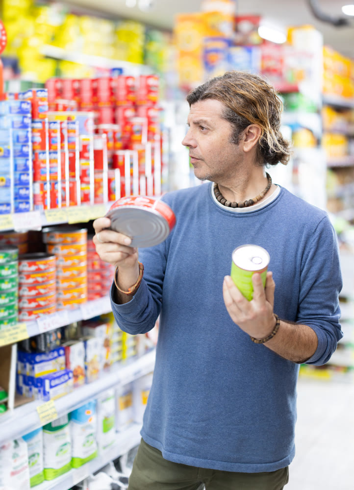 Adult man selects canned goods at grocery store