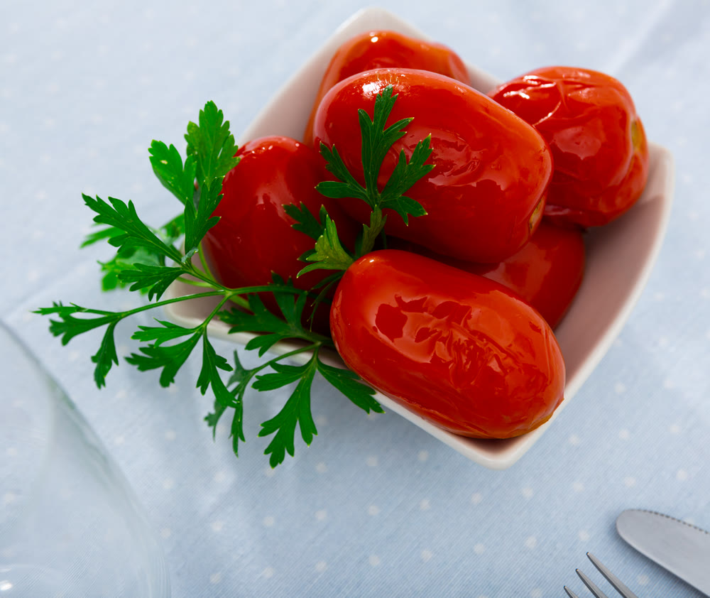 Marinated tomatoes served on white plate decorated with parsle