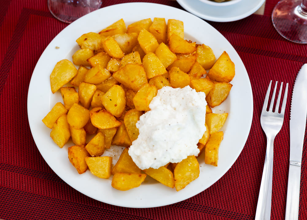 Spicy Spanish tapa Patatas bravas, baked potatoes pieces with aioli sauce