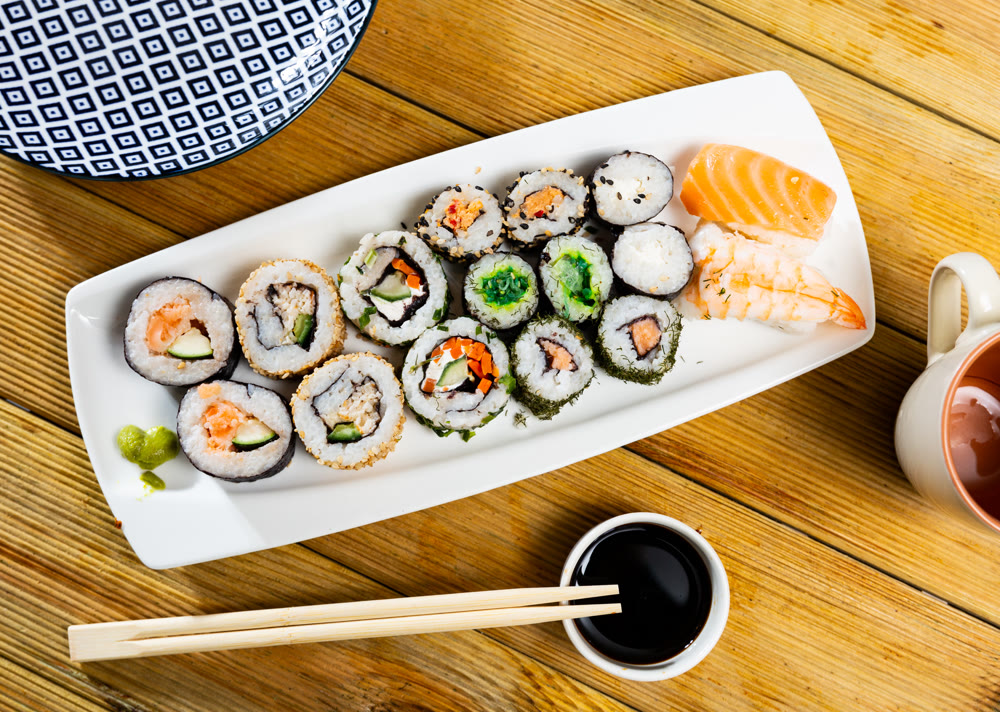Set of different types of sushi served with sauce soy on board in cafe