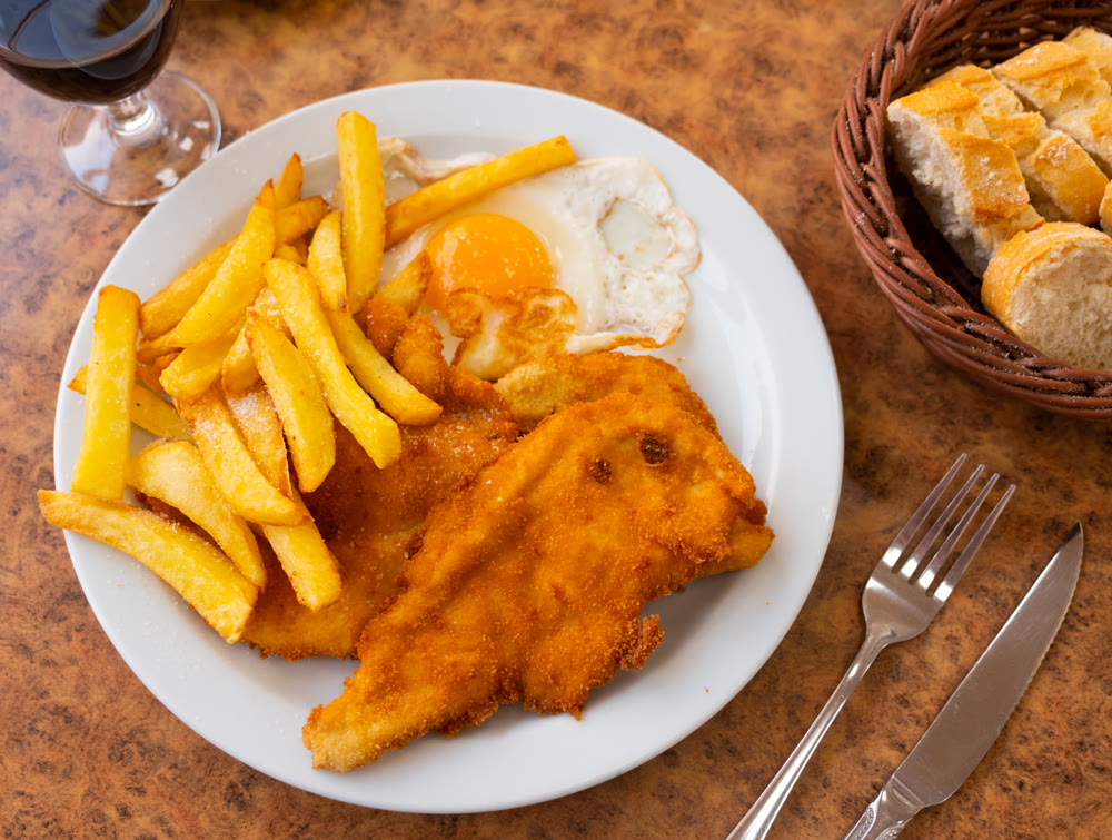 Breaded veal served with fried egg and french fries