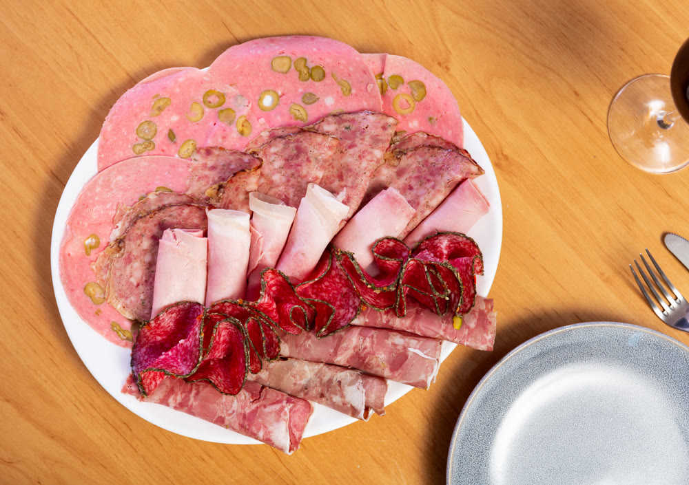 Slices of butifarra and smoked sausage dished up in a service plate on laid restaurant table
