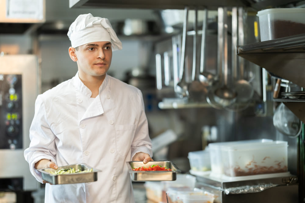 Young male cook carrying ingredients in restaurant kitchen