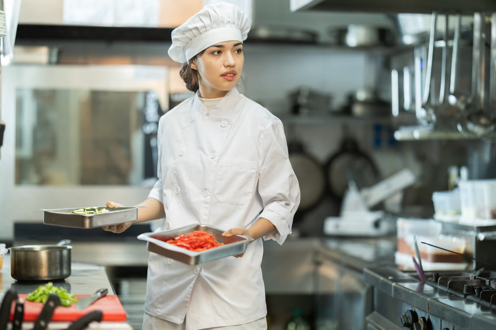 Young female chef chops ingredients for dish