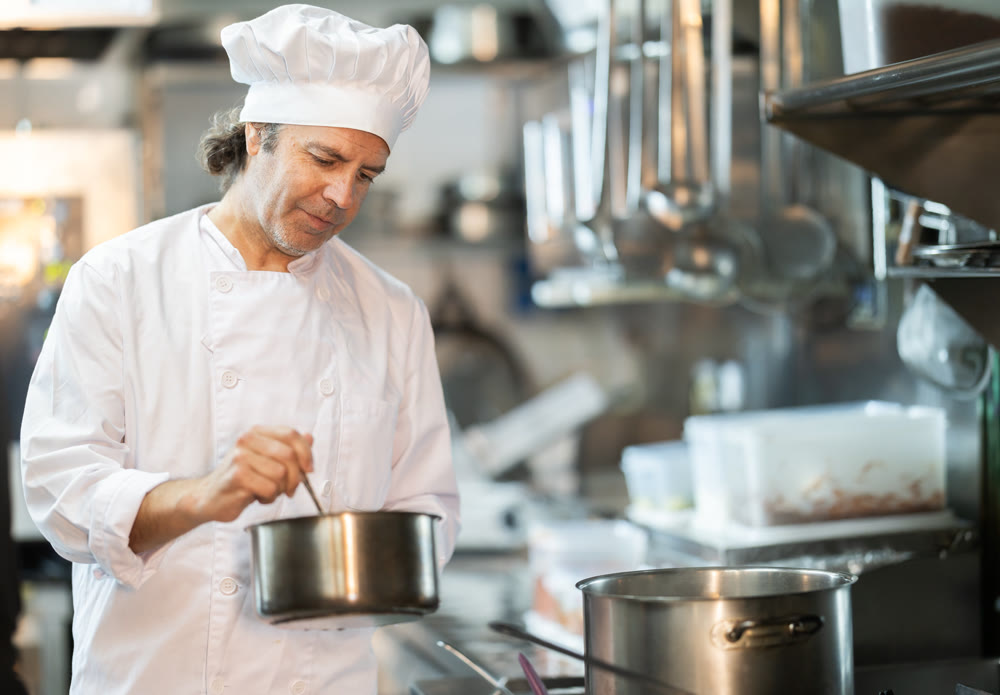 Man cook in kitchen is working near stove