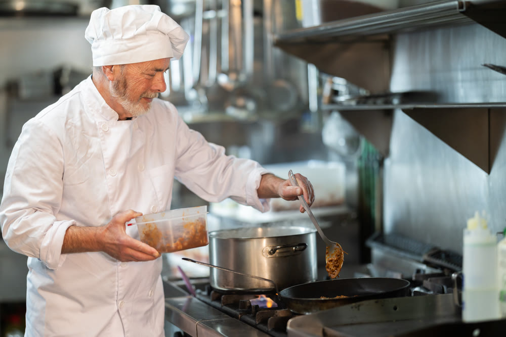 Senior male cook preparing dish in restaurant kitchen
