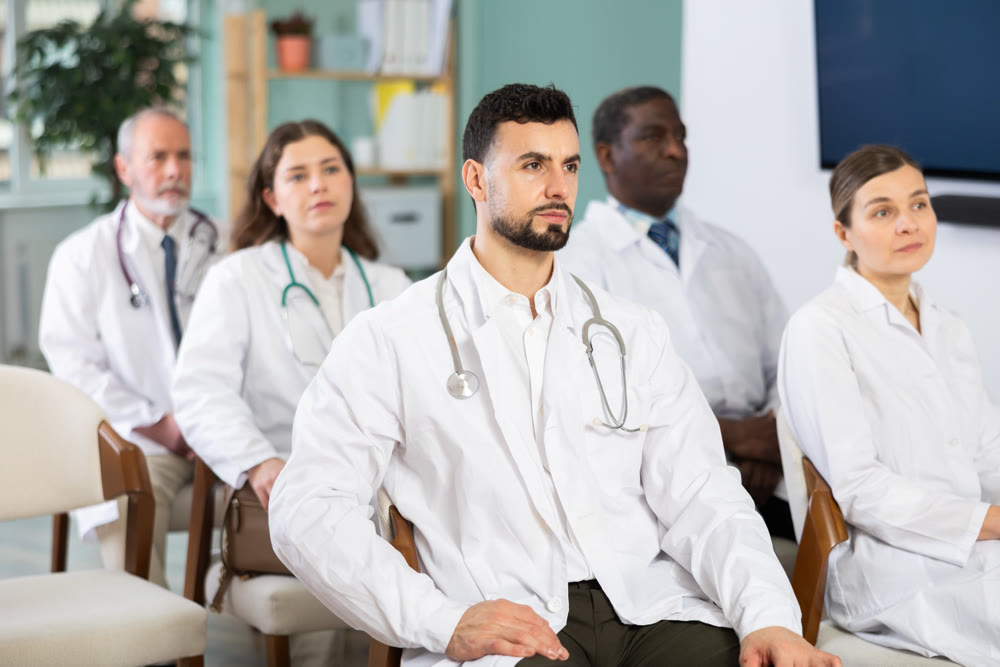 Male doctor listens to lecture with colleagues in auditorium