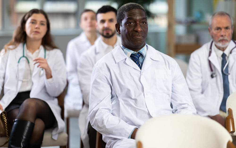 African man doctor student at courses meeting listens to teacher and look at speaker