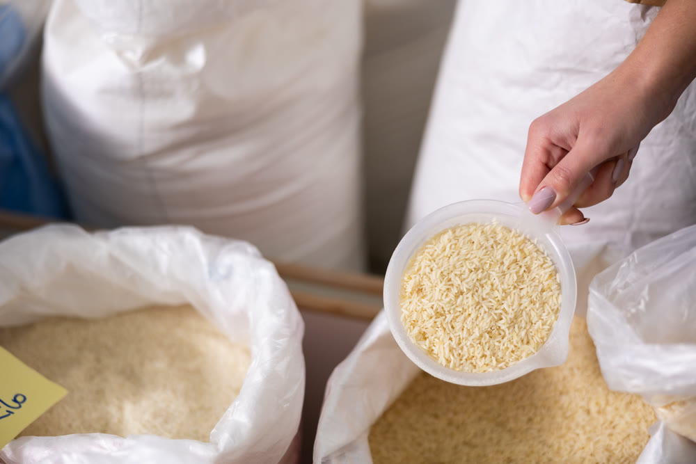 Woman's hand scooping basmati rice from bag in store