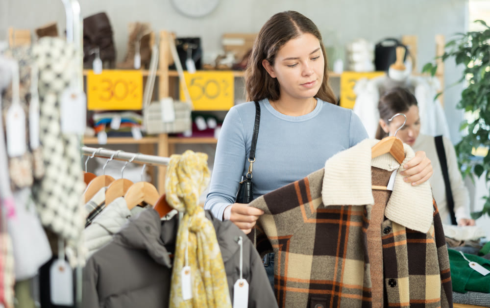 Young woman chooses plaid jacket in clothing store