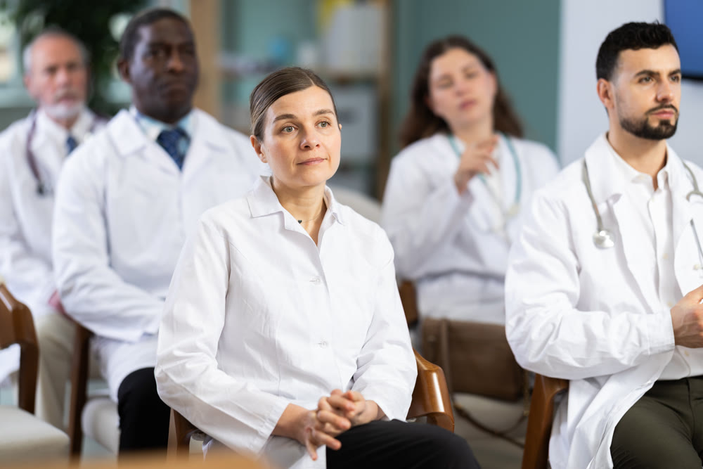 Woman doctor student at courses meeting listens to teacher and look at speaker