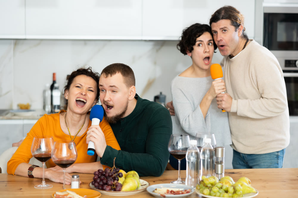 Party and karaoke at house for fun social event or gathering together in celebration. Happy people celebrating friendship, birthday or festive season singing at home