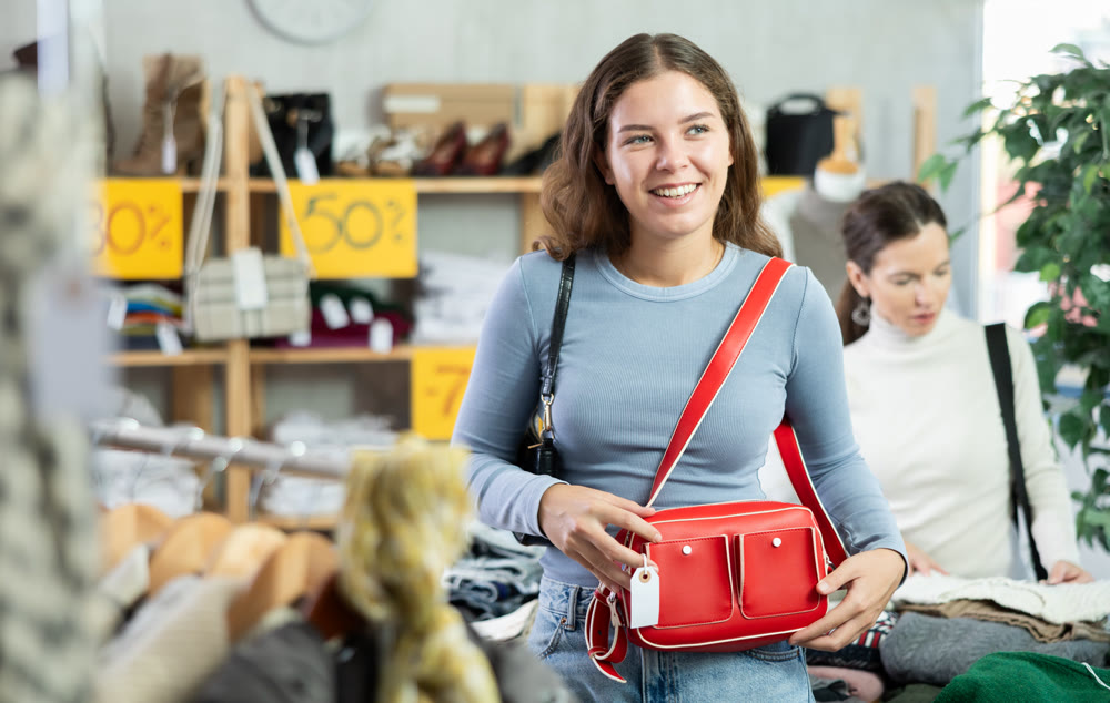 Selective young girl choosing handbag in clothing store