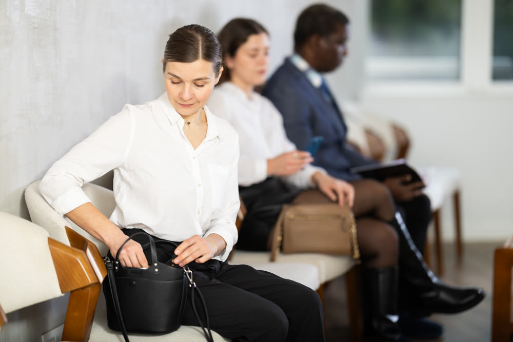 Adult woman sitting in job interview queue in office