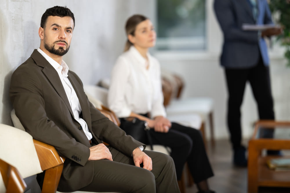 Young man sitting in job interview queue in office