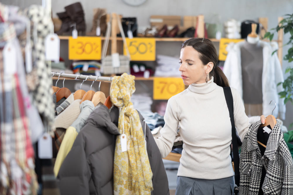 Adult woman chooses coat in clothing store