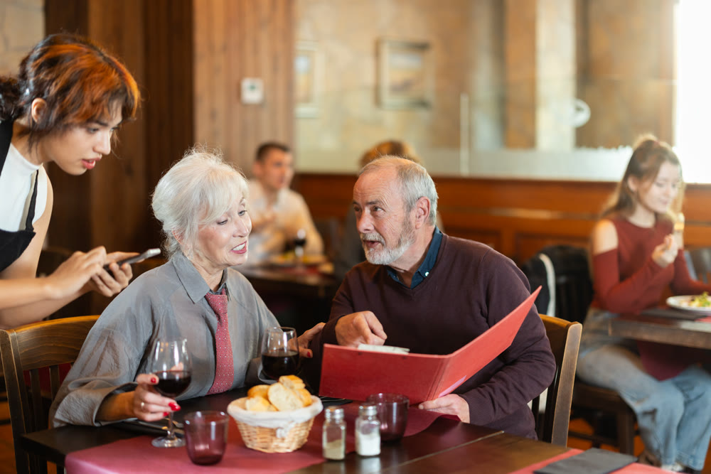 Young female waitress takes order from elderly couple