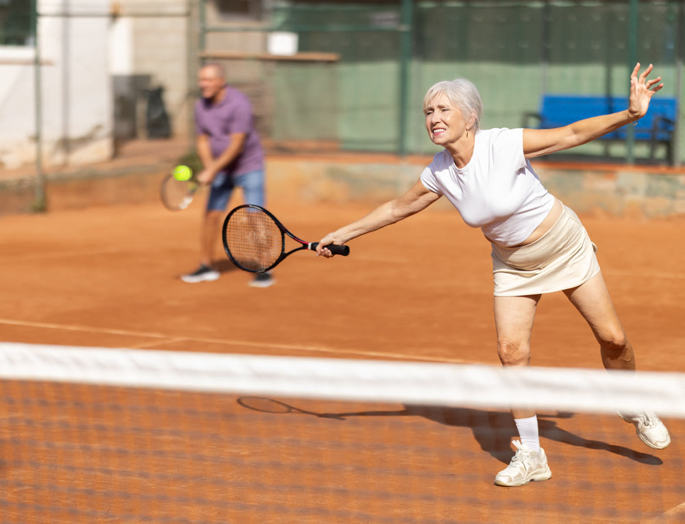 Elderly couple playing tennis together in court