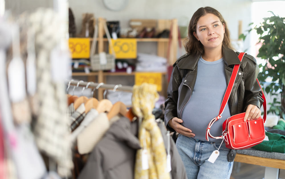 Pregnant woman choosing handbag in clothing store