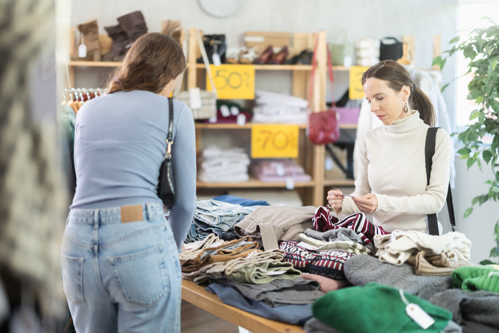 Happy woman chooses fashionable sweater for autumn winter season in store