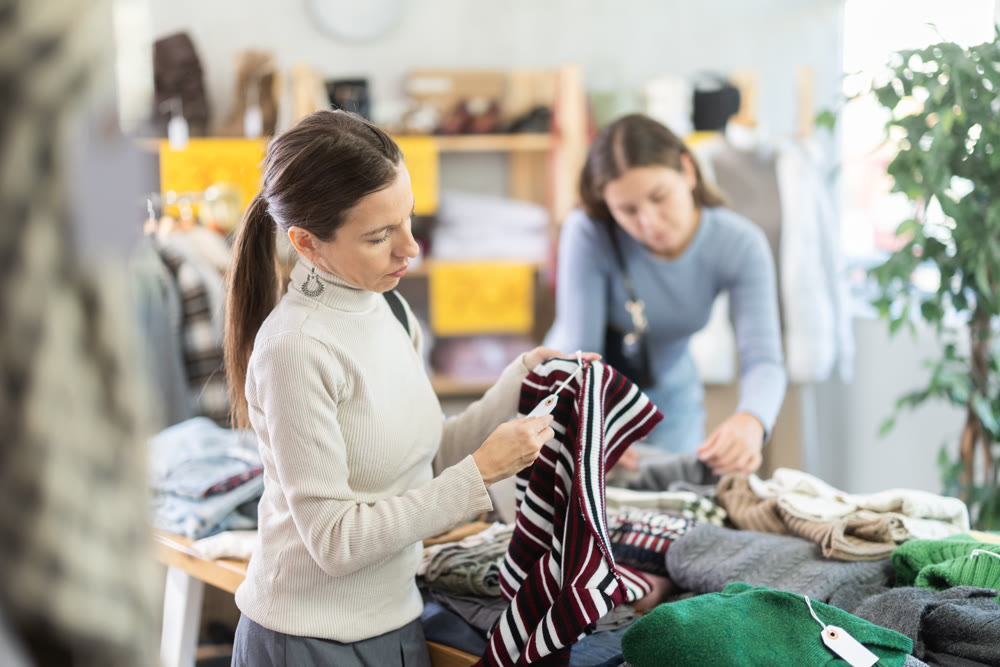 Adult woman chooses sweater in clothing store