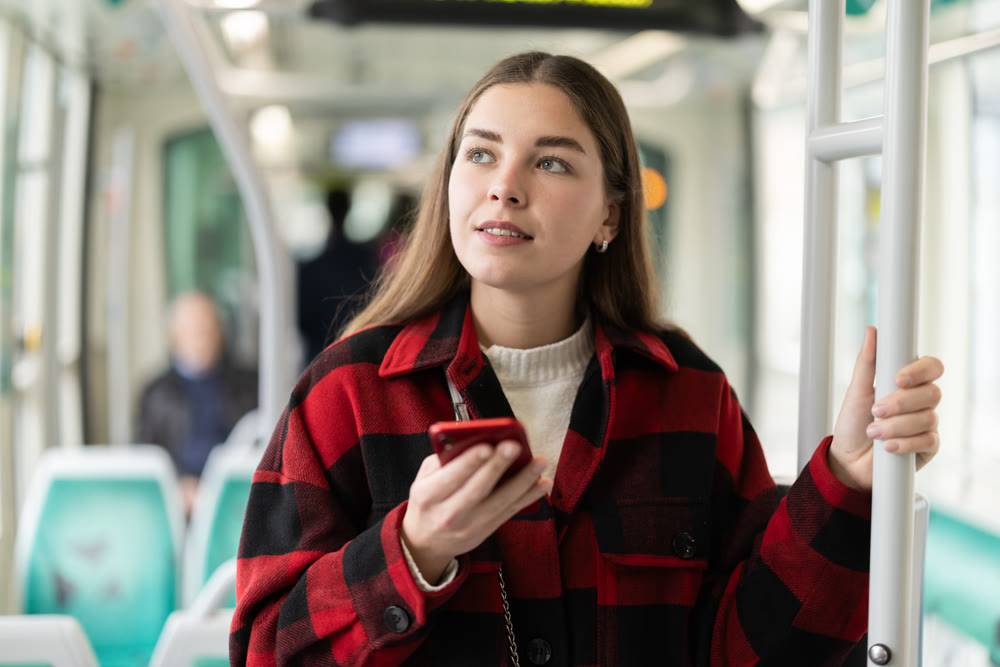 Girl with long hair standing in tram with phone