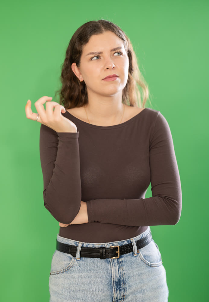 Young woman confused and forgetful in front of green screen