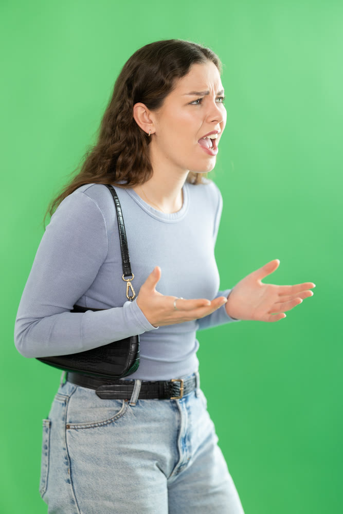 Young woman angry and yelling in front of green screen