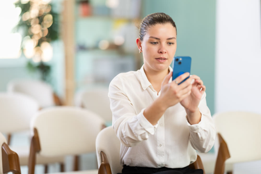 Young female student taking photo on smartphone at training