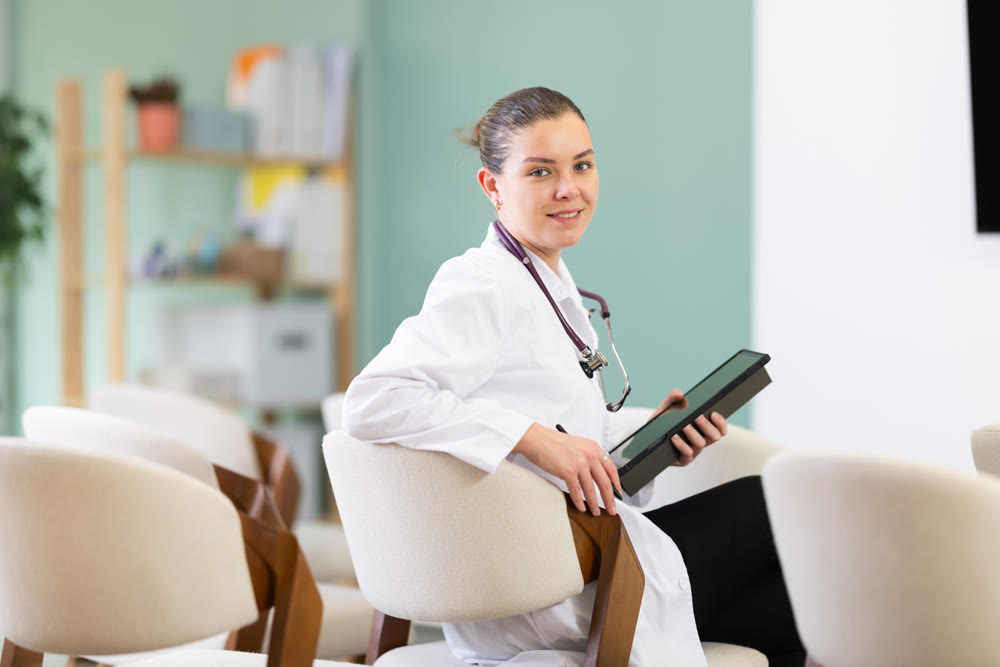 Female medical student listening to lecture in classroom with tablet