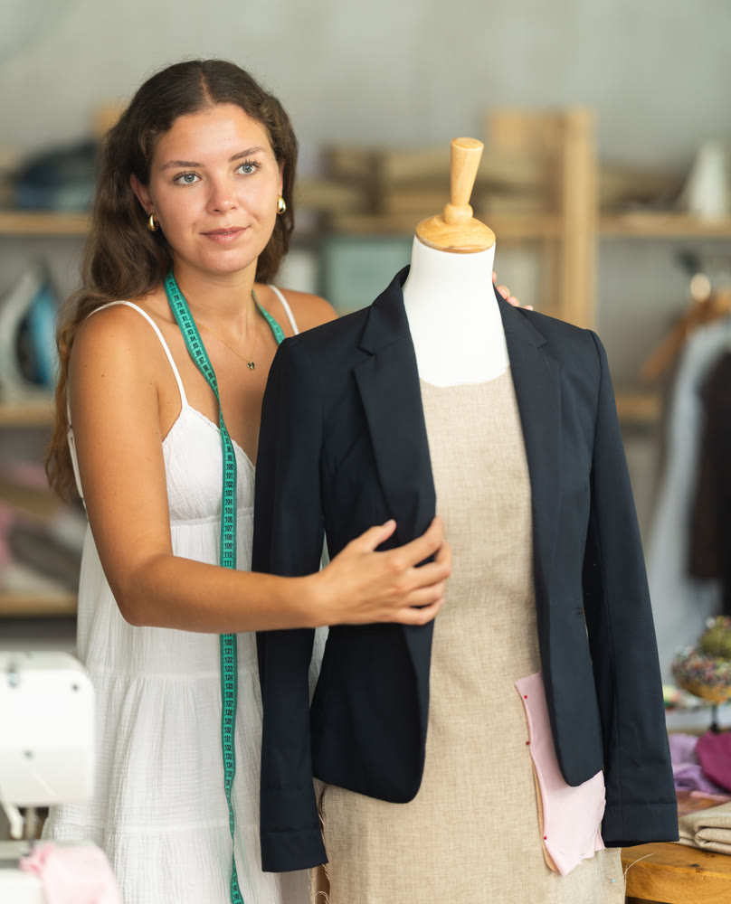 dressmaker checks the quality of a sewn jacket in the workshop