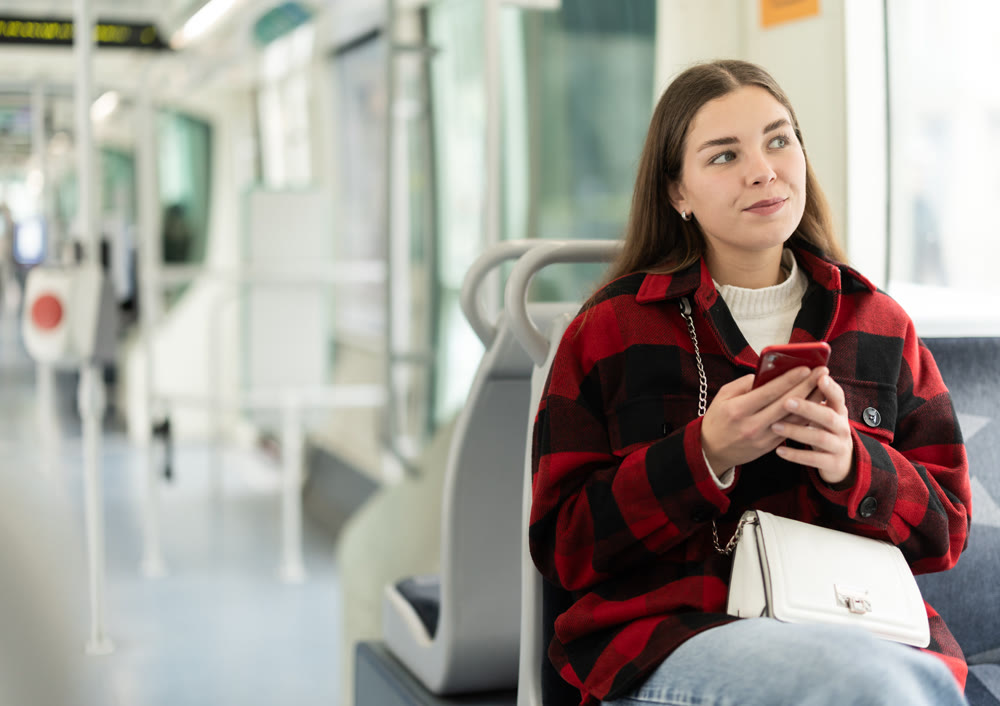 Woman sitting in tram car with phone