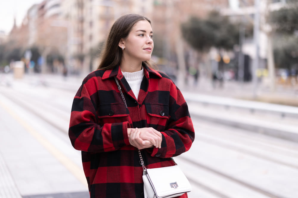 woman stands at a public transport stop