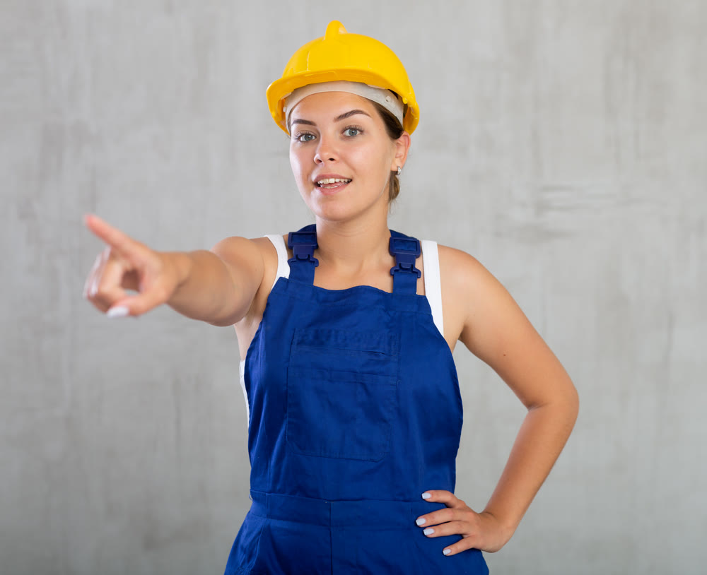 Young woman posing in work overalls in studio