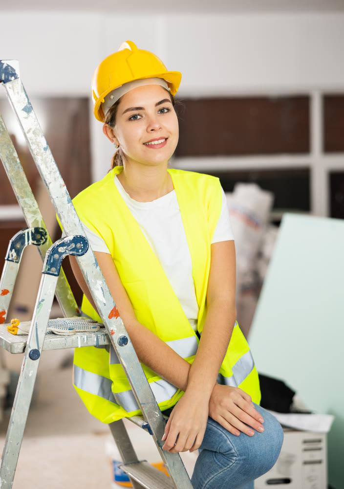 Woman builder sitting on stepladder in apartment