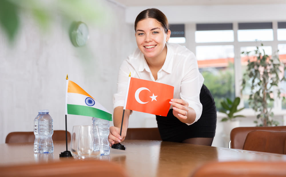 Young female attendant putting up flags for international negotiations between india and turkey
