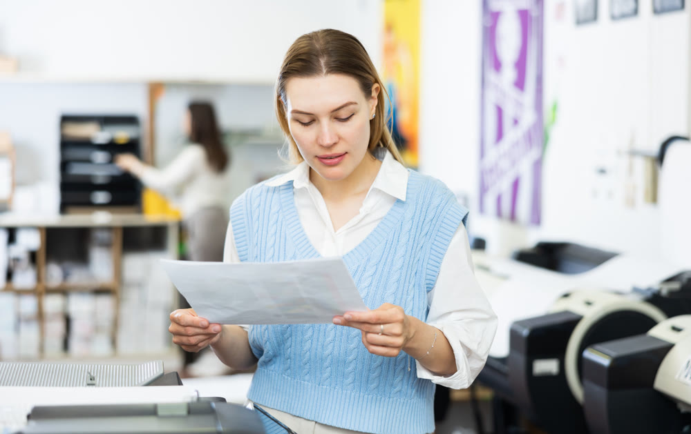 Portrait of an attentive woman checking the quality of printing in printing house
