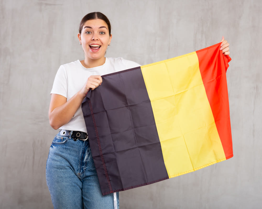 Happy girl stands with flag of Belgium .Isolated