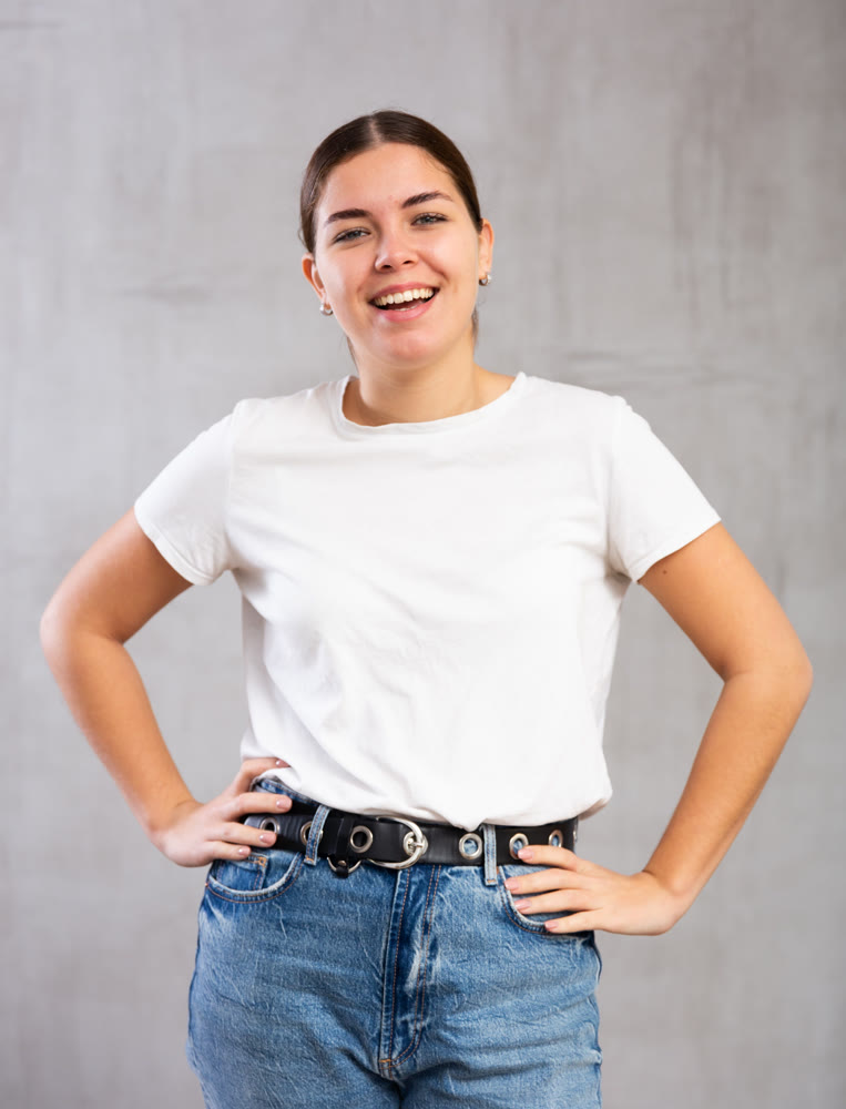 Cheery young woman posing happily against gray background